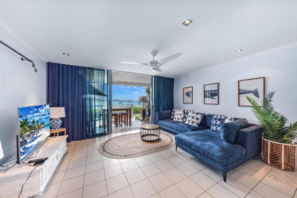 a living room with a blue couch and a tv at By The Sea Shore With Pool in Airlie Beach