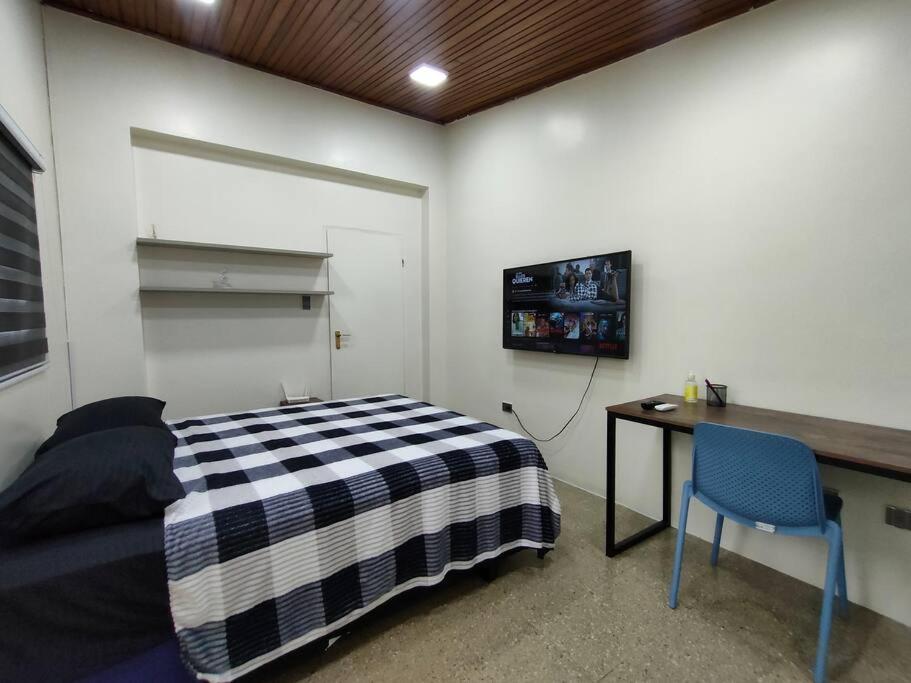 a bedroom with a bed and a desk and a tv at Hermosa suite acogedora, Las Garzas in Guayaquil