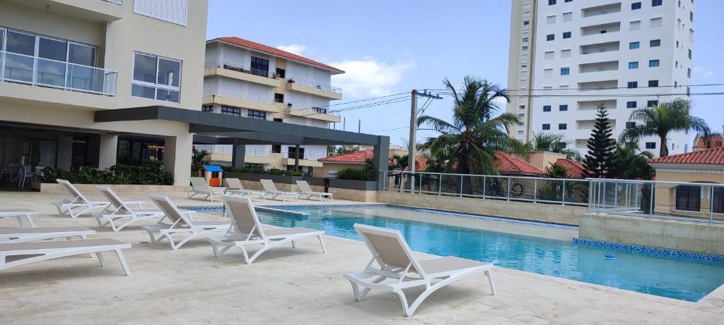 a swimming pool with lounge chairs next to a building at Moreno Paradise en Playa Juan Dolio in Los Corrales