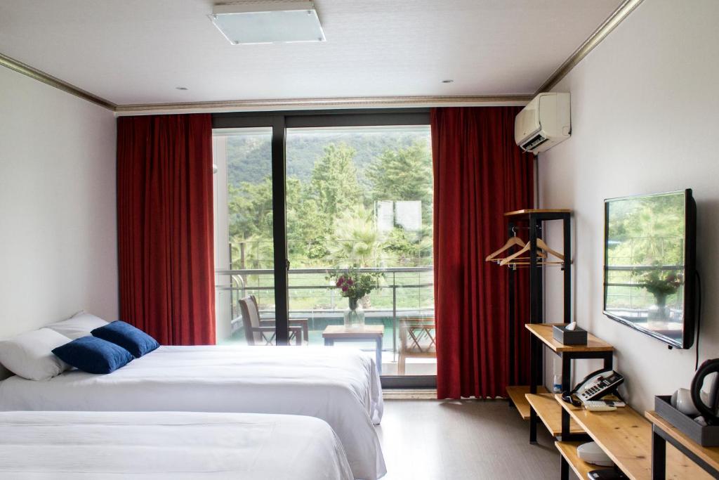 a hotel room with two beds and a large window at Dammora Resort in Seogwipo