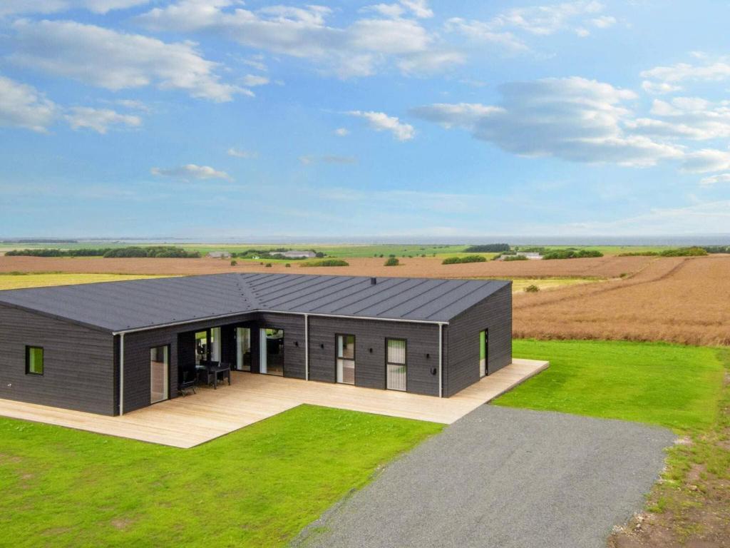 a house with a black roof in a field at 12 person holiday home in Lemvig-By Traum in Lemvig