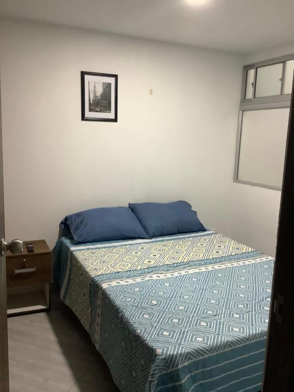 a bedroom with a bed with blue sheets and a window at Cómoda habitación con baño privado in Sabaneta