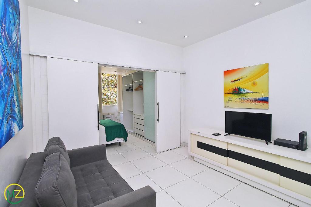Hotel Studio com vista lateral para o mar em Copacabana, a living room with a couch and a flat screen tv at Studio com vista lateral para o mar em Copacabana in Rio de Janeiro