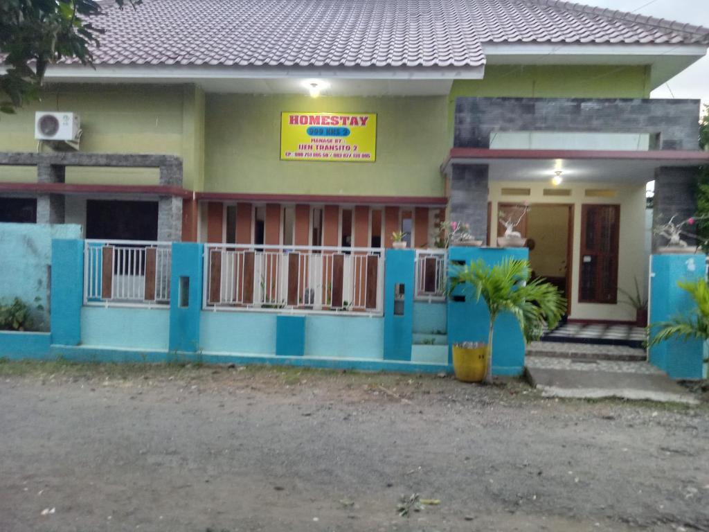 a house with a blue front porch and a yellow sign at Ijen Transito 2 HOMESTAY in Ketapang