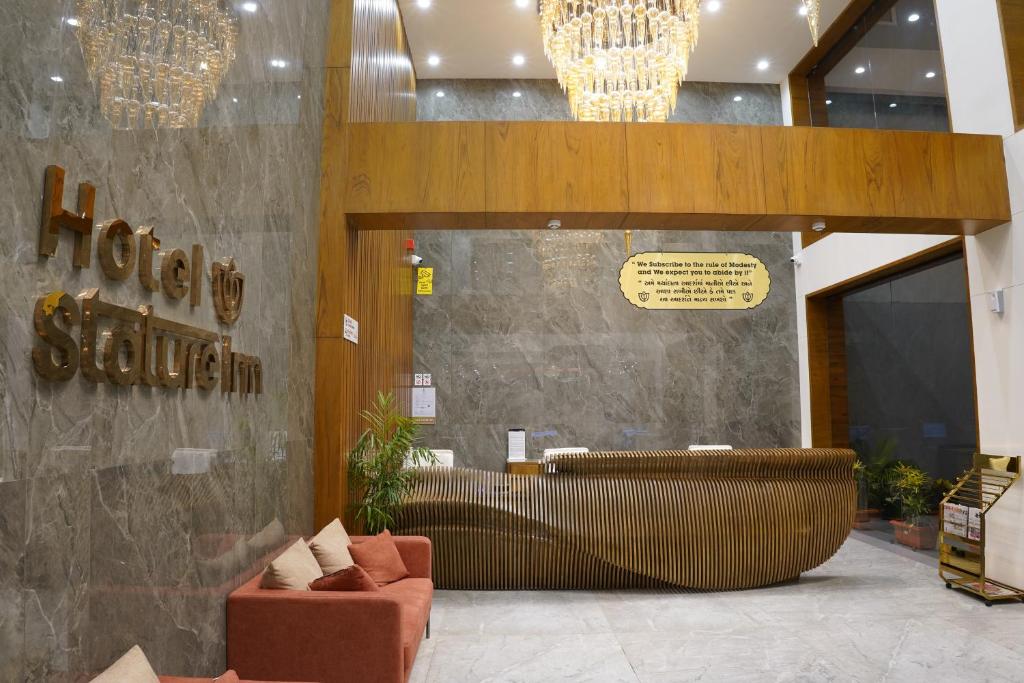 a lobby with a brown sofa and a sign on the wall at HOTEL STATURE INN in Kevadia