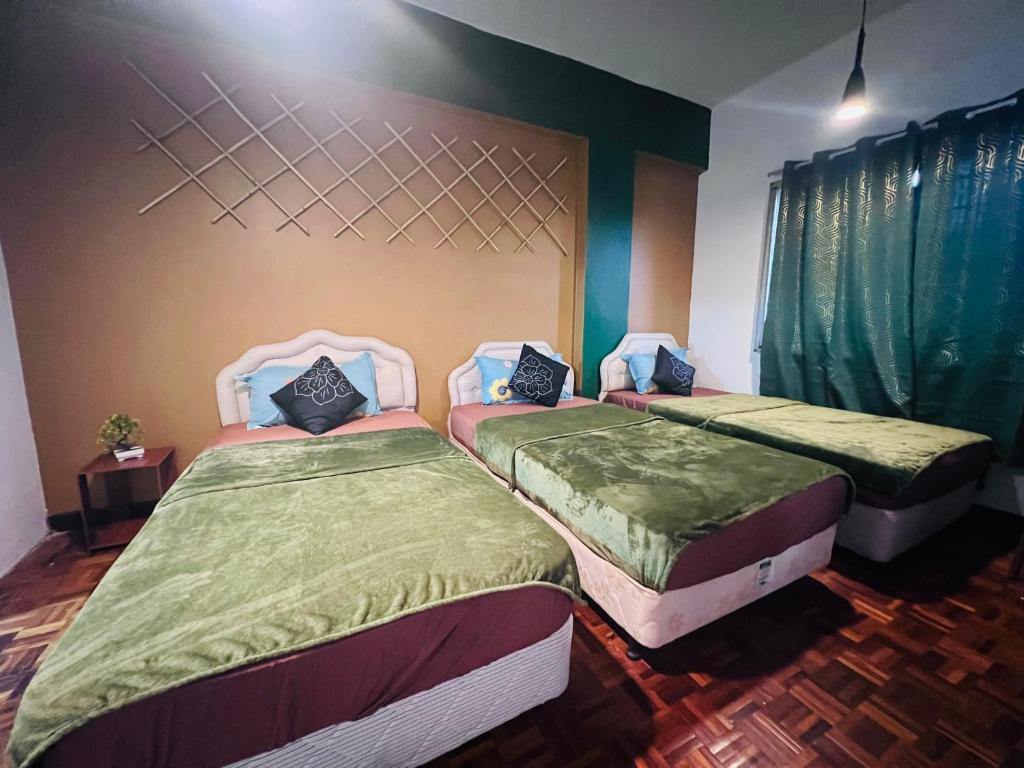 zwei Einzelbetten in einem Zimmer mit grüner Bettwäsche in der Unterkunft The Heritage@Selesa Hillhomes Bukit Tinggi Berjaya Hills Bentong in Bentong