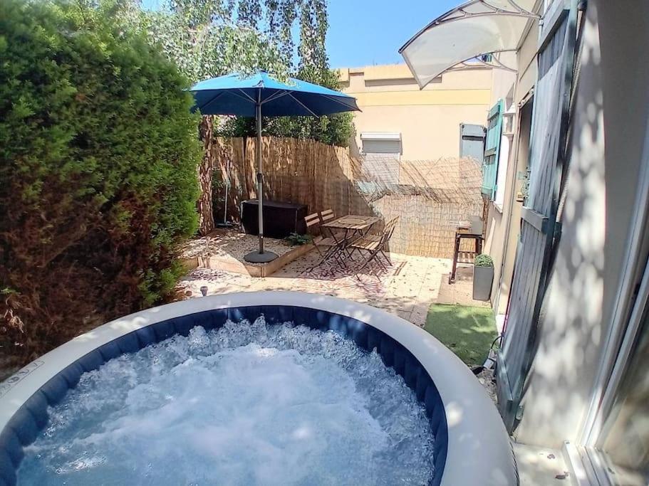 een hot tub met water en een paraplu bij Le petit Marc in Kingersheim