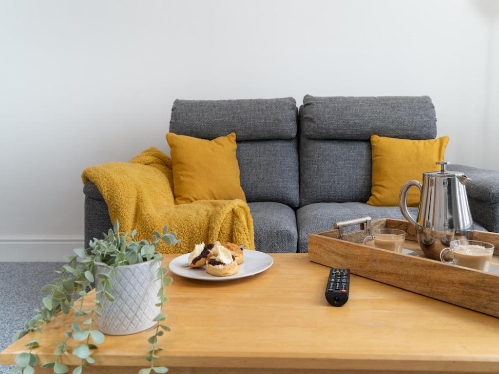 a coffee table with a plate of food on a couch at Bright~ Town Center~ 2 bed~Penzance in Penzance