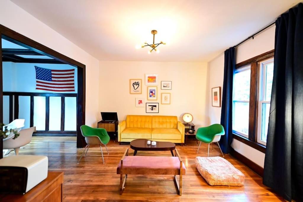 a living room with a yellow couch and green chairs at Luxe Mid-Century Styled Historic Townhouse #2 in Detroit