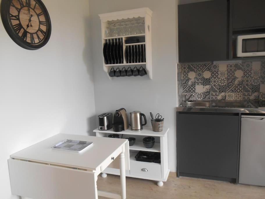 een keuken met een witte tafel en een klok aan de muur bij T2 - Résidence Plein Sud in Cabourg