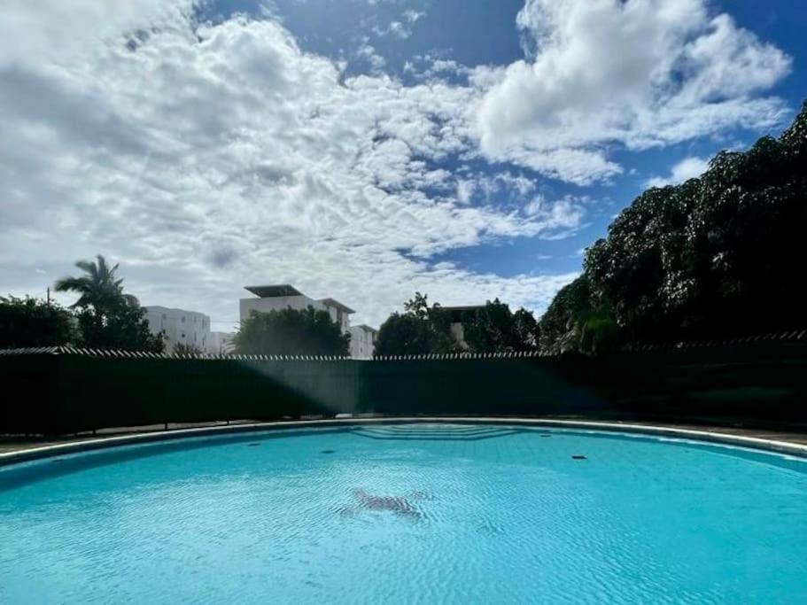 a large blue swimming pool with a sky background at L appart dans les Nuages - Climatisé - Piscine - Vues panoramiques - Proche aéroport et Université in Sainte-Clotilde