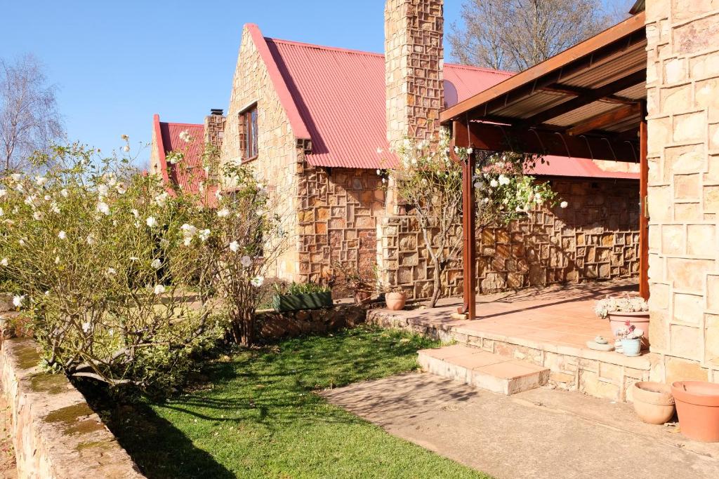 a house with a stone building and a yard at Mountain View Cottage in Dullstroom