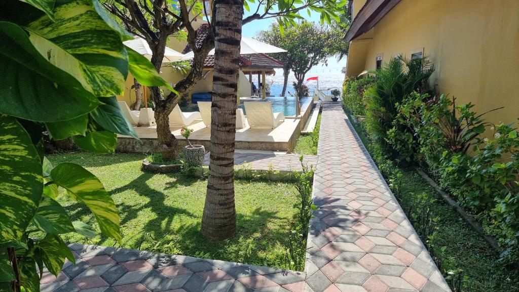 une passerelle à côté d'une maison avec des arbres et de l'herbe dans l'établissement Nalini Resort, à Amed