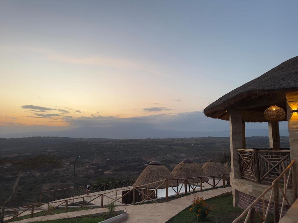 a group of thatch roofs on a building with a view at Africa Safari Karatu in Karatu