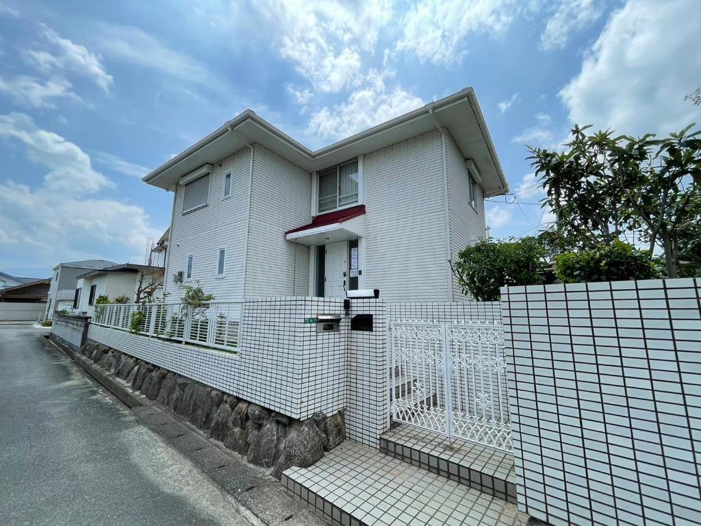een wit huis met een hek ervoor bij Prime 糸島 in Itoshima