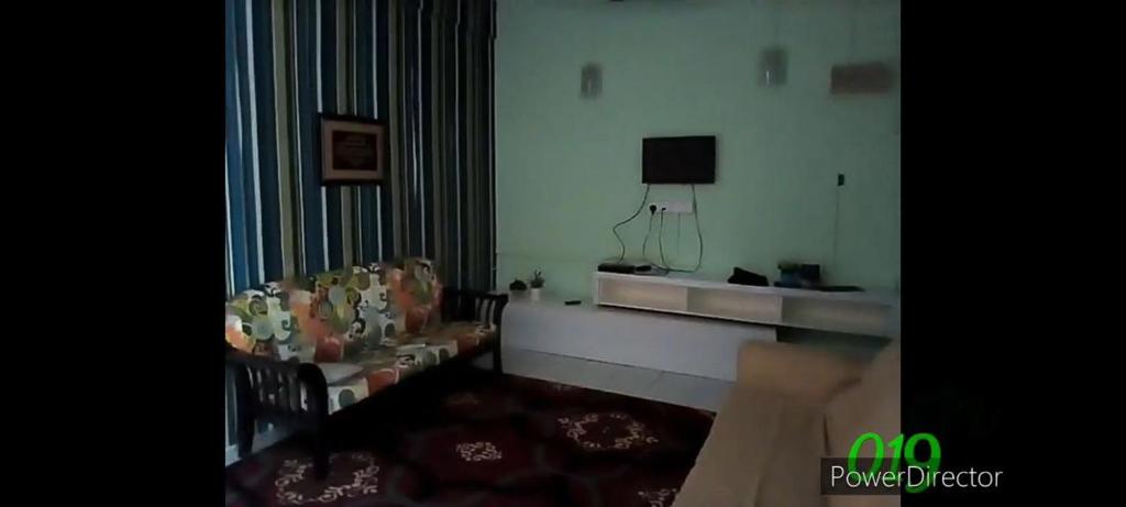a living room with a couch and a television at Iman Homestay in Papar