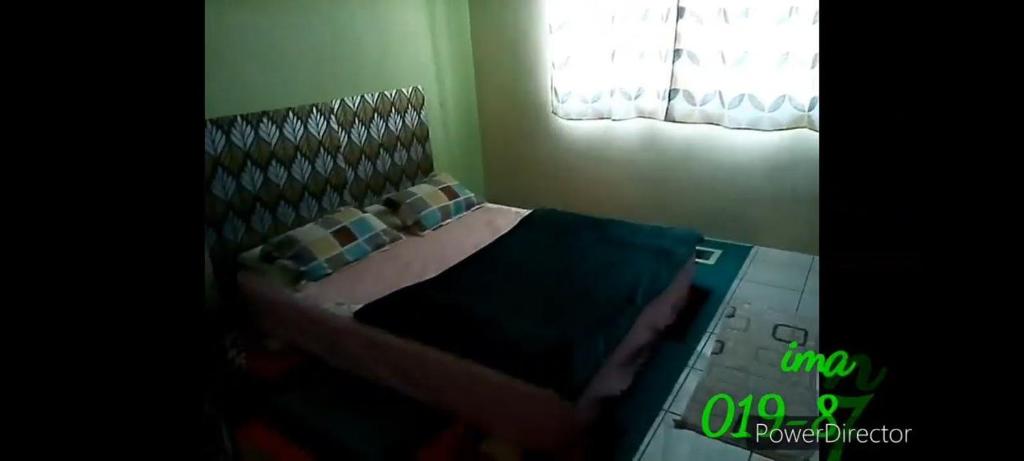 - une chambre avec un lit doté d'oreillers et d'une fenêtre dans l'établissement Iman Homestay, à Papar