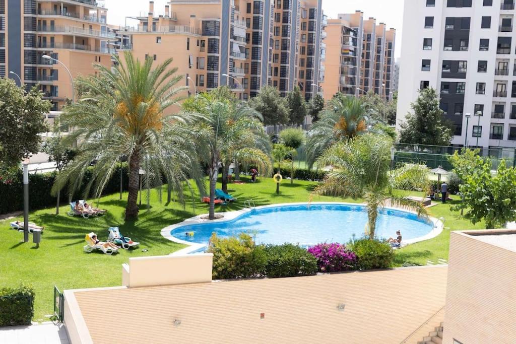 Blick auf einen Pool in einem Park mit Palmen in der Unterkunft Modern apartment, Pool & Air con, San Juan Playa in Alicante