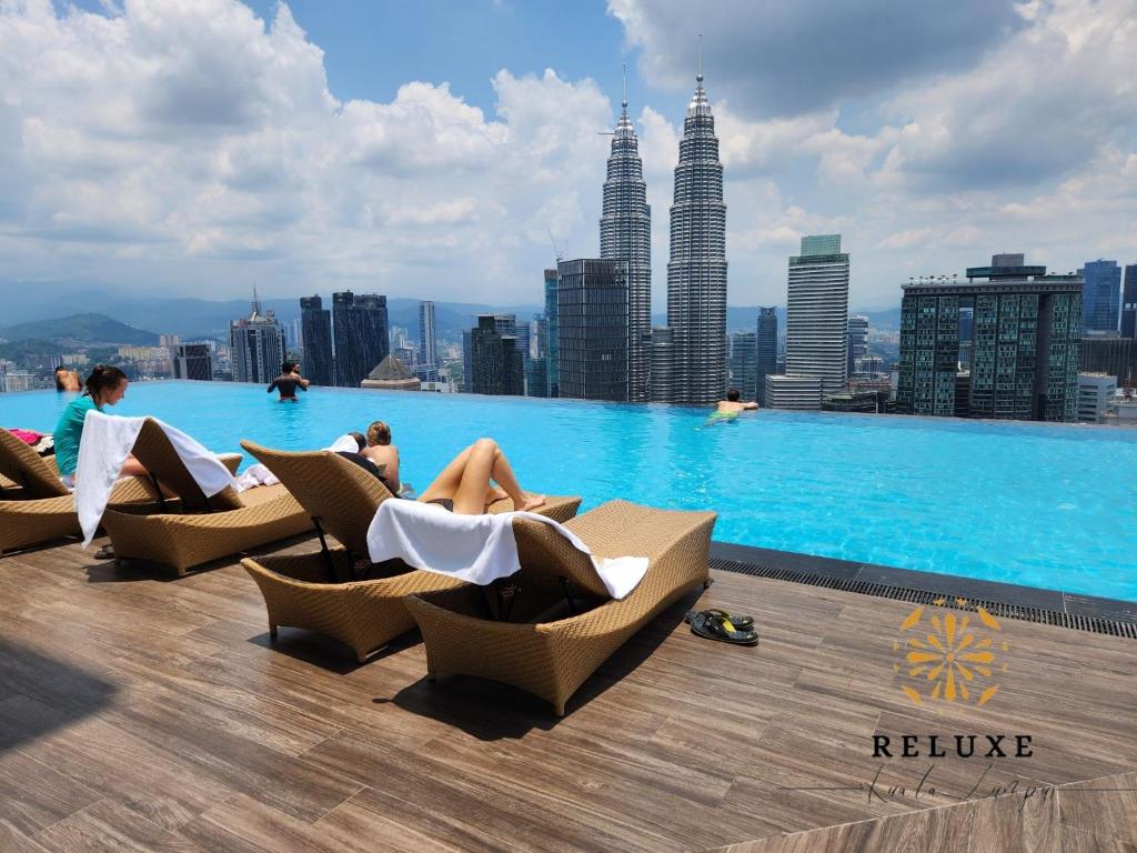 una piscina con gente sentada en sillas en la azotea de un edificio en The Platinum 2 KLCC Premium Suite by Reluxe Kuala Lumpur en Kuala Lumpur