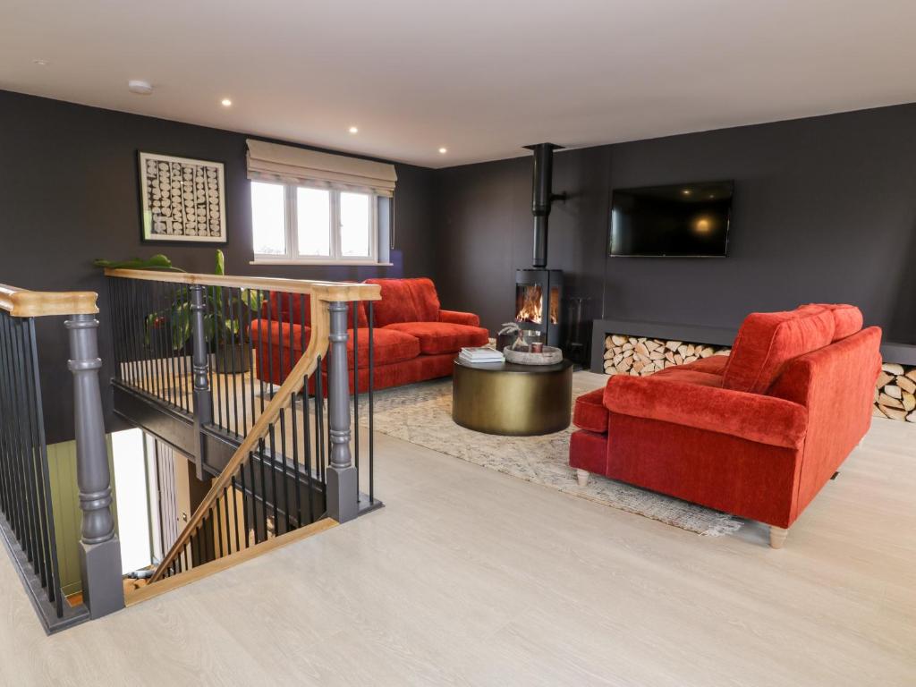 uma sala de estar com mobiliário vermelho e uma televisão em Farmyard House em Amlwch