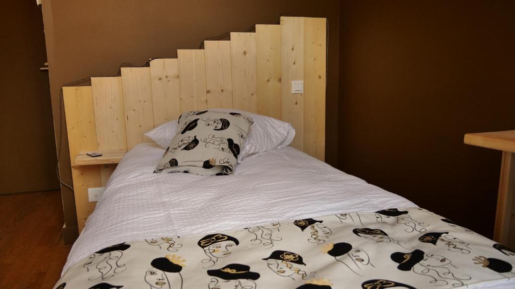 a bed with a wooden headboard and pillows on it at Relais des Monts du Lyonnais in Les Halles