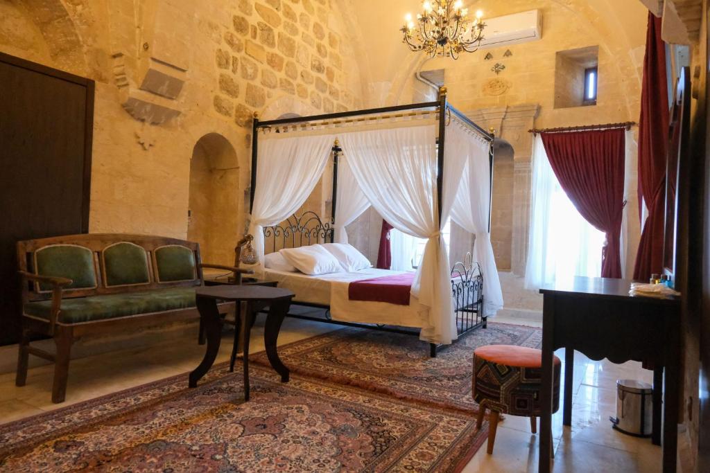 a bedroom with a canopy bed and a table and a piano at MİRSTONE TARİHİ KONAK in Mardin