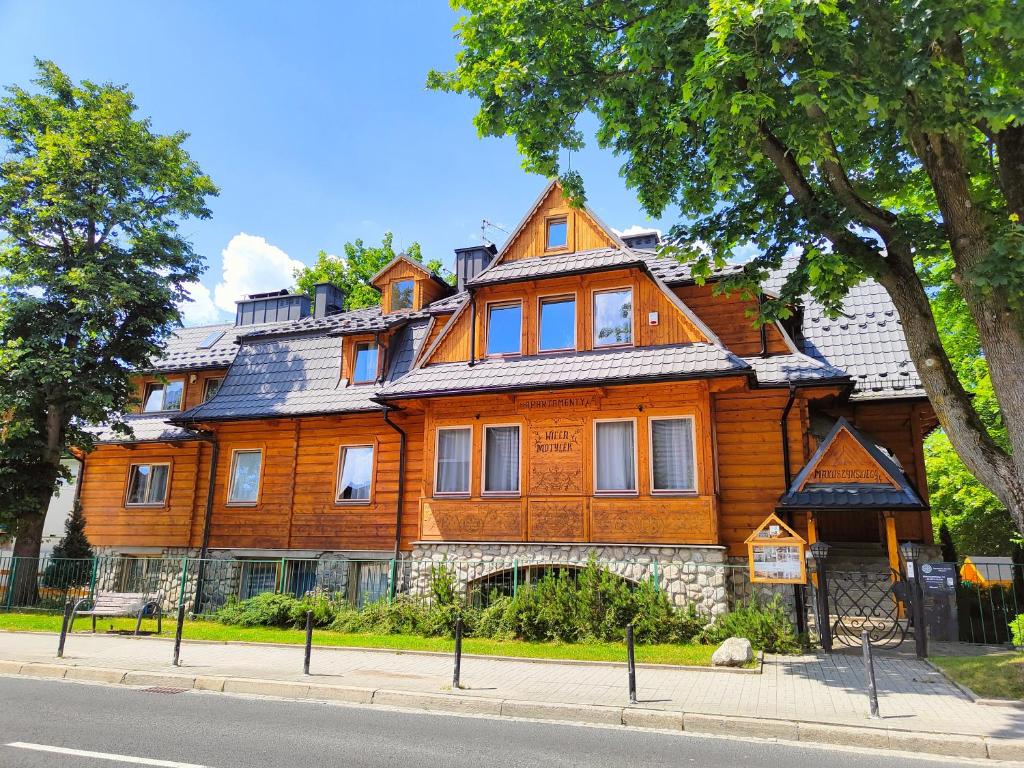 una gran casa de madera en el lateral de la calle en Apartamenty ApartArt Zakopane, en Zakopane