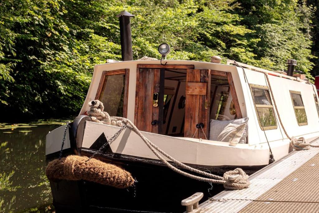 SNUG 30ft NARROWBOAT WITH FIREPLACE في Bishopbriggs: قارب مربوط على رصيف في الماء