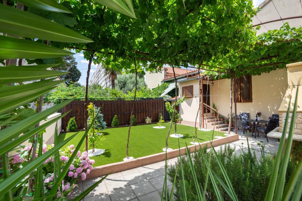 a garden with a patio and a lawn with plants at Antique Garden Villa in Split