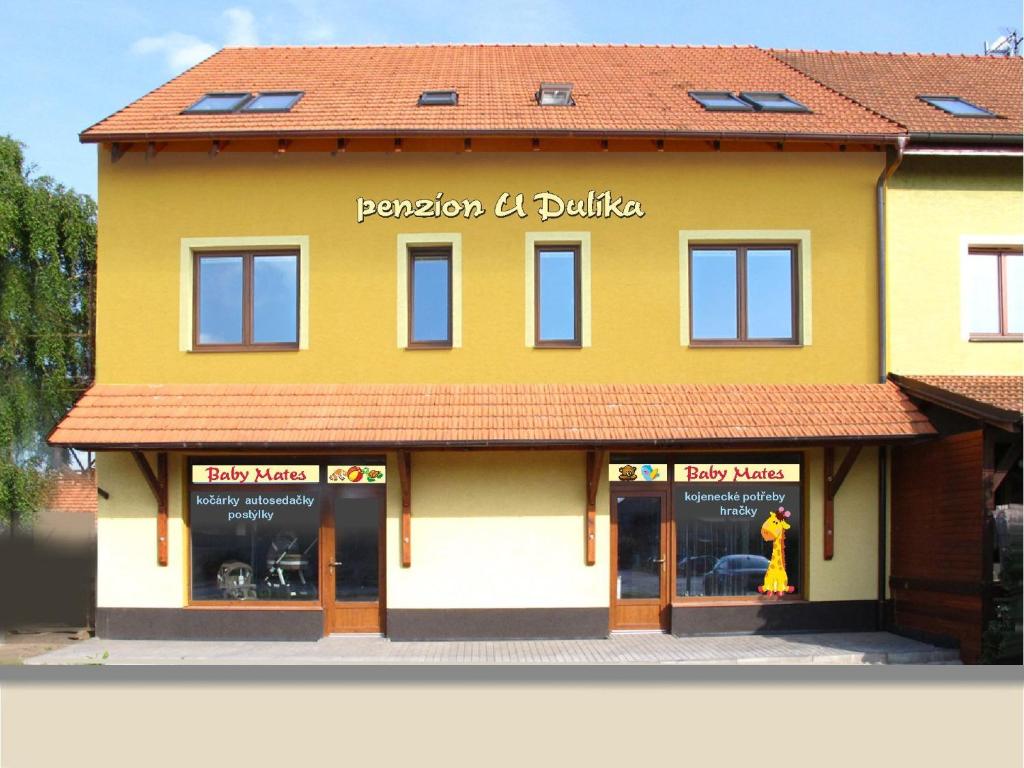 a yellow building with windows and a yellow fire hydrant at Penzion U Dulíka in Veselí nad Moravou