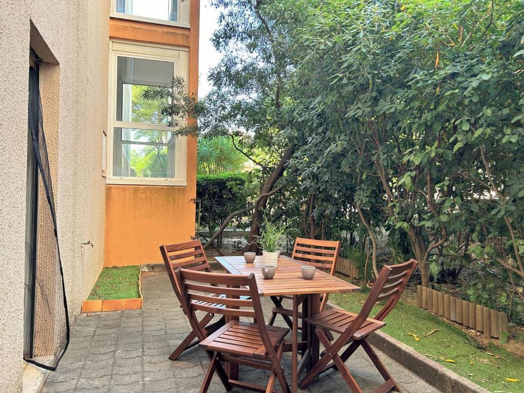 une table et des chaises en bois sur une terrasse dans l'établissement Appartement T2 avec Jardin, Parking et Climatiseur - Proche Plage Bormes-les-Mimosas - FR-1-251-436, à Bormes-les-Mimosas