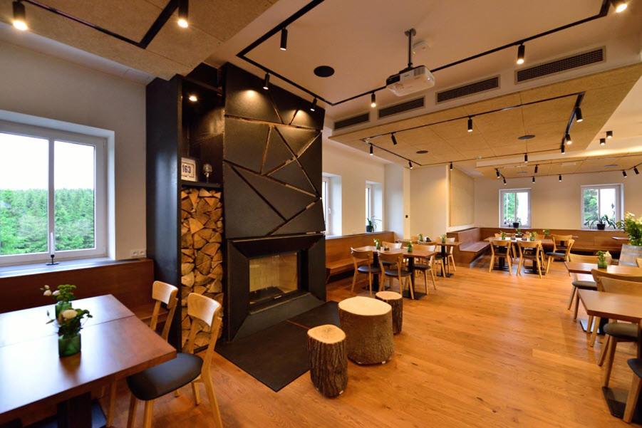un ristorante con tavoli, sedie e un camino di Horská chata Smědava a Weissbach