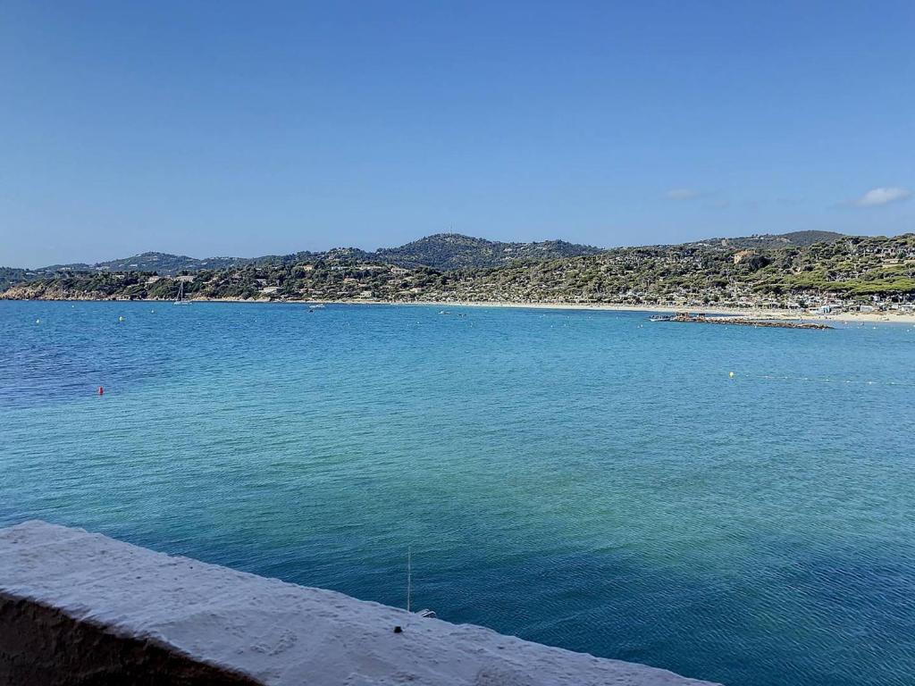 une grande étendue d'eau avec une plage en arrière-plan dans l'établissement T3 avec piscine à 100m de la plage à Bormes-les-Mimosas - FR-1-610-11, à Bormes-les-Mimosas