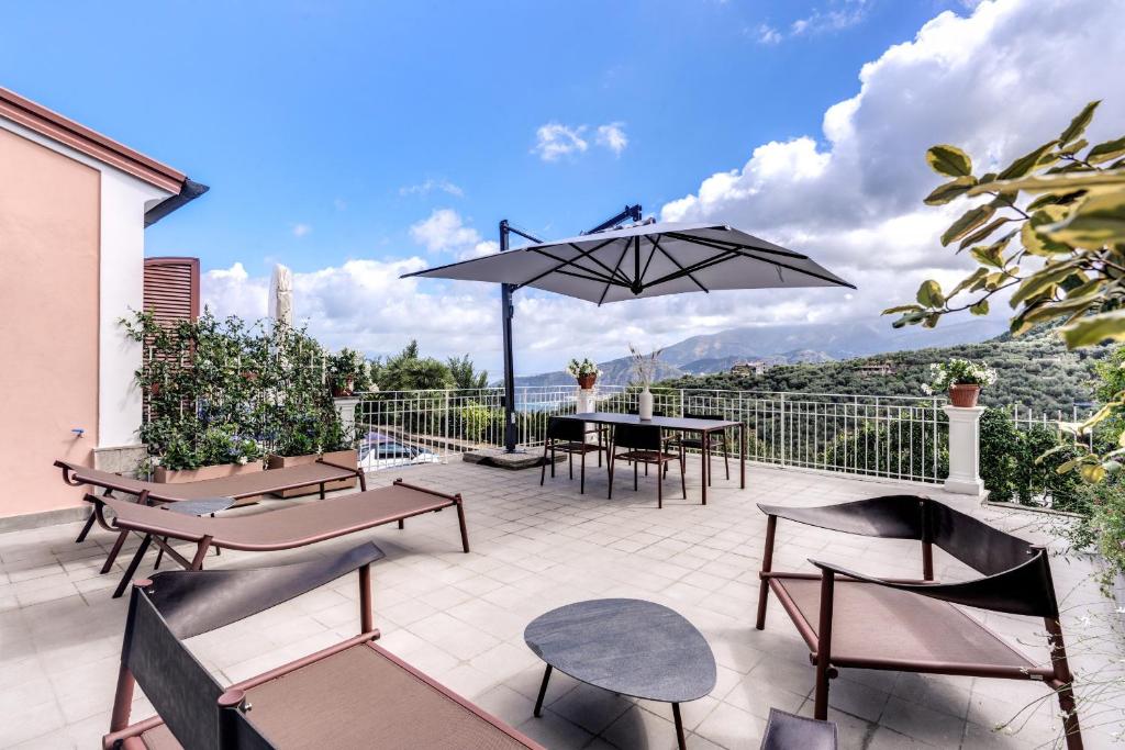 eine Terrasse mit Tischen, Stühlen und einem Sonnenschirm in der Unterkunft Suite La Panoramica in Massa Lubrense