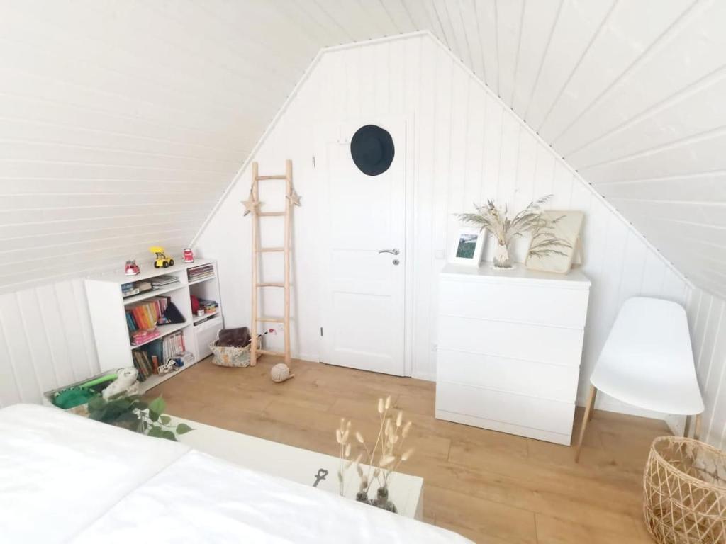 a white attic room with a white bed and a ladder at Hafenhaus Panoramablick mit Sauna & Whirlpool in Wandlitz