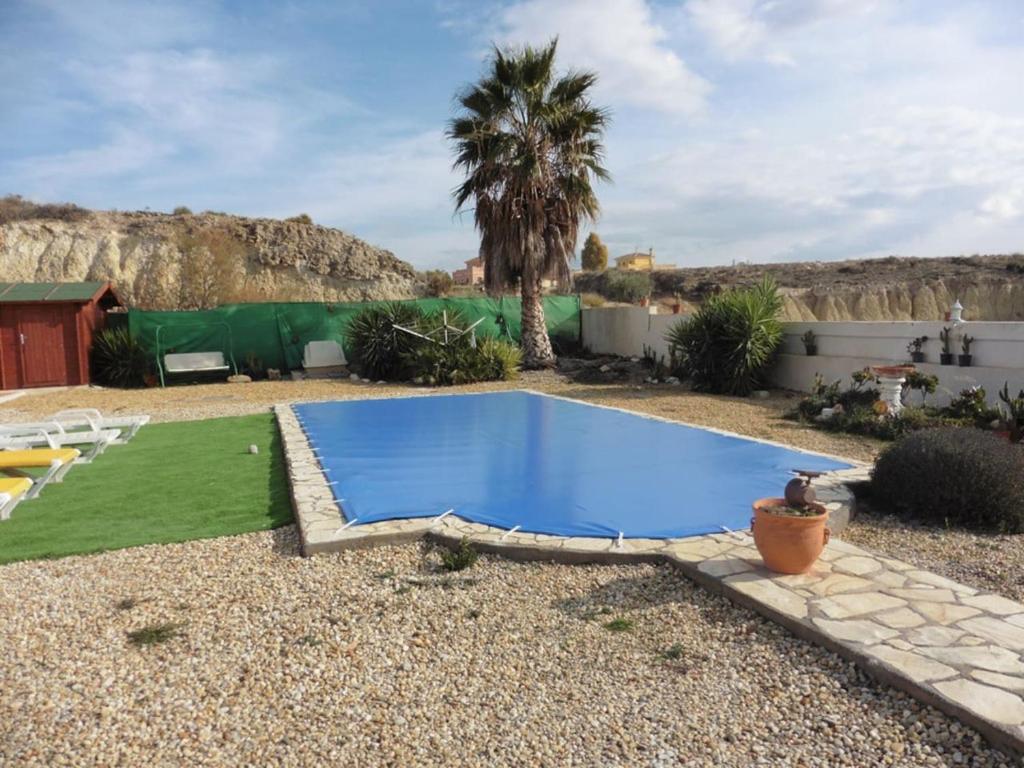 a small blue swimming pool in a yard with a green lawn at Lovely 1 bedroom attached apartment with kitchen but private with seasonable pool in Albox