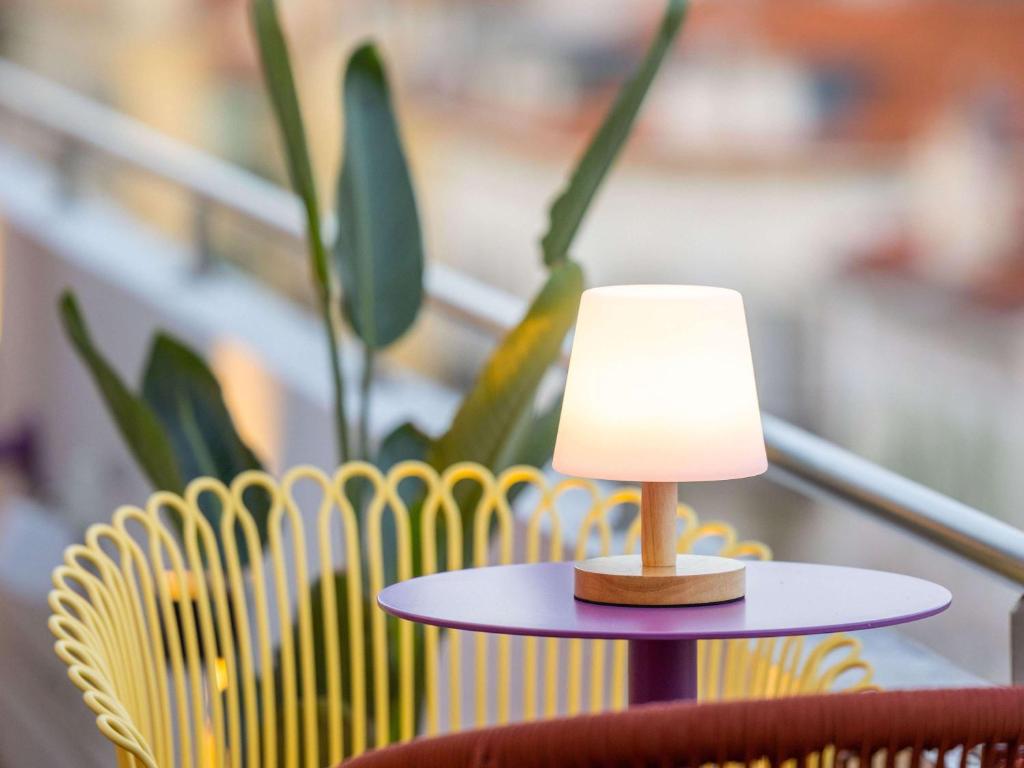 una lámpara en una mesa junto a una silla amarilla en Mercure Nice Centre Notre Dame, en Niza