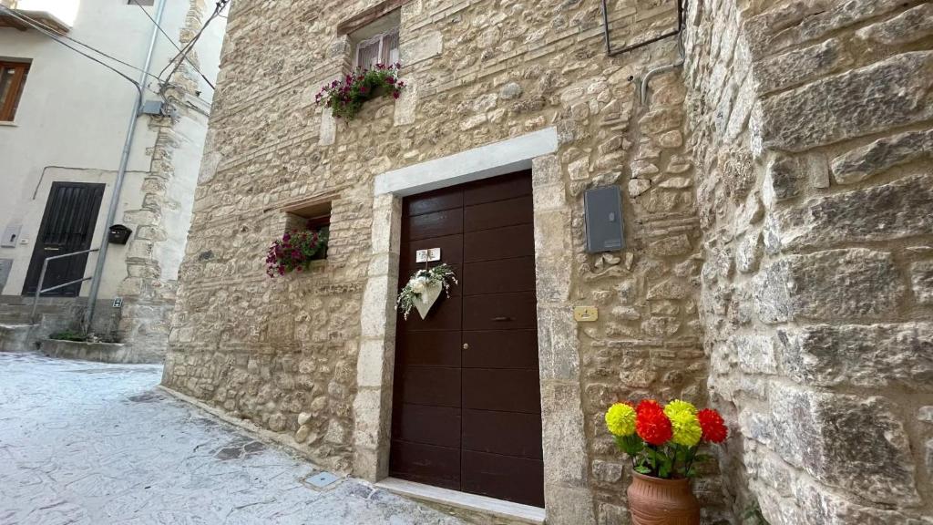 - un bâtiment en briques avec une porte marron ornée de fleurs dans l'établissement Casa Vacanze MarGiu, à Goriano Sicoli