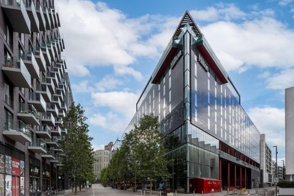 un edificio di vetro alto con tetto a punta di Hilton London Wembley a Londra