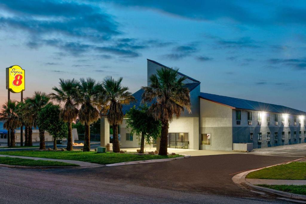 a building with palm trees in front of a street at Super 8 by Wyndham New Braunfels I-35 in New Braunfels