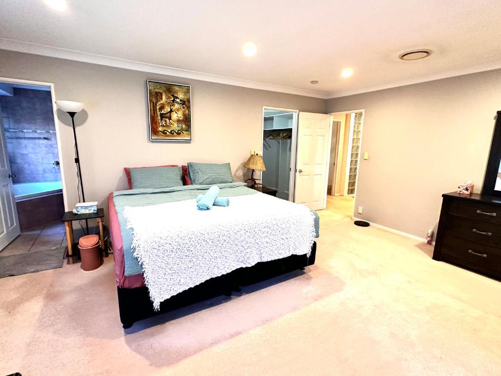 een slaapkamer met een bed en een dressoir bij West Harbour White House (西港白宫） in Auckland