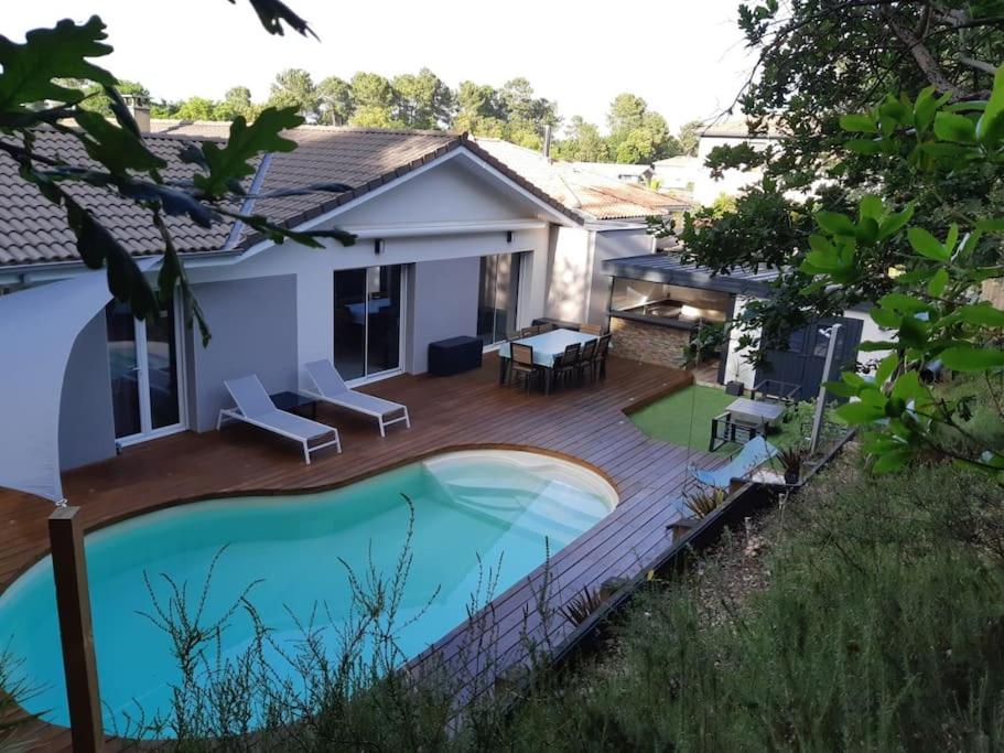 een achtertuin met een houten terras en een zwembad bij Jolie maison moderne et sereine à Labenne in Labenne
