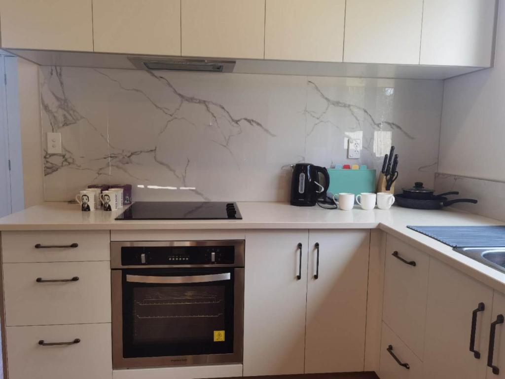 eine Küche mit weißen Schränken und einem schwarzen Backofen in der Unterkunft Henderson New House (瀚德森新居） in Auckland
