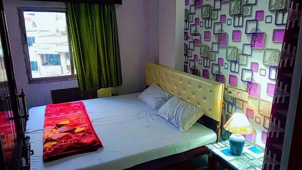 a bed in a room with a wall with a window at Shree Krishna Hotel in Udaipur