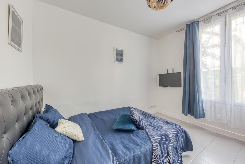 1 dormitorio con cama con sábanas azules y ventana en Appartement Moderne, proche Porte de Versailles et Gare de Clamart, en Malakoff