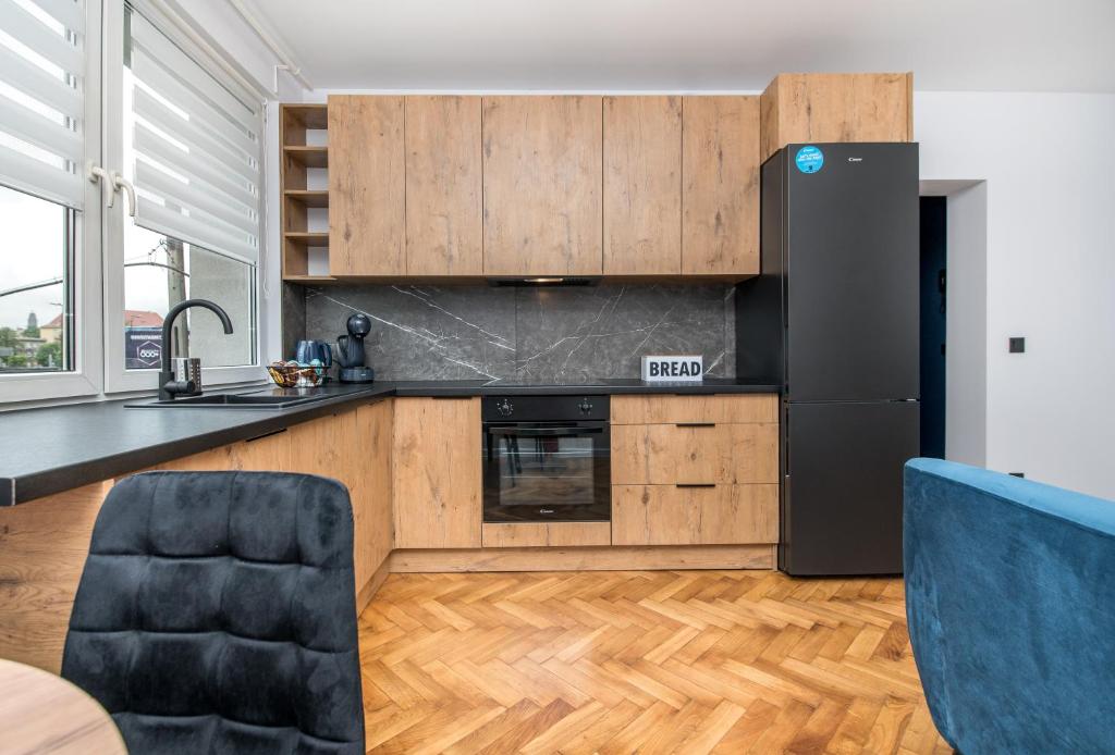 eine Küche mit Holzschränken und einem schwarzen Kühlschrank in der Unterkunft Apartament Jagielońska 1/3 in Gliwice