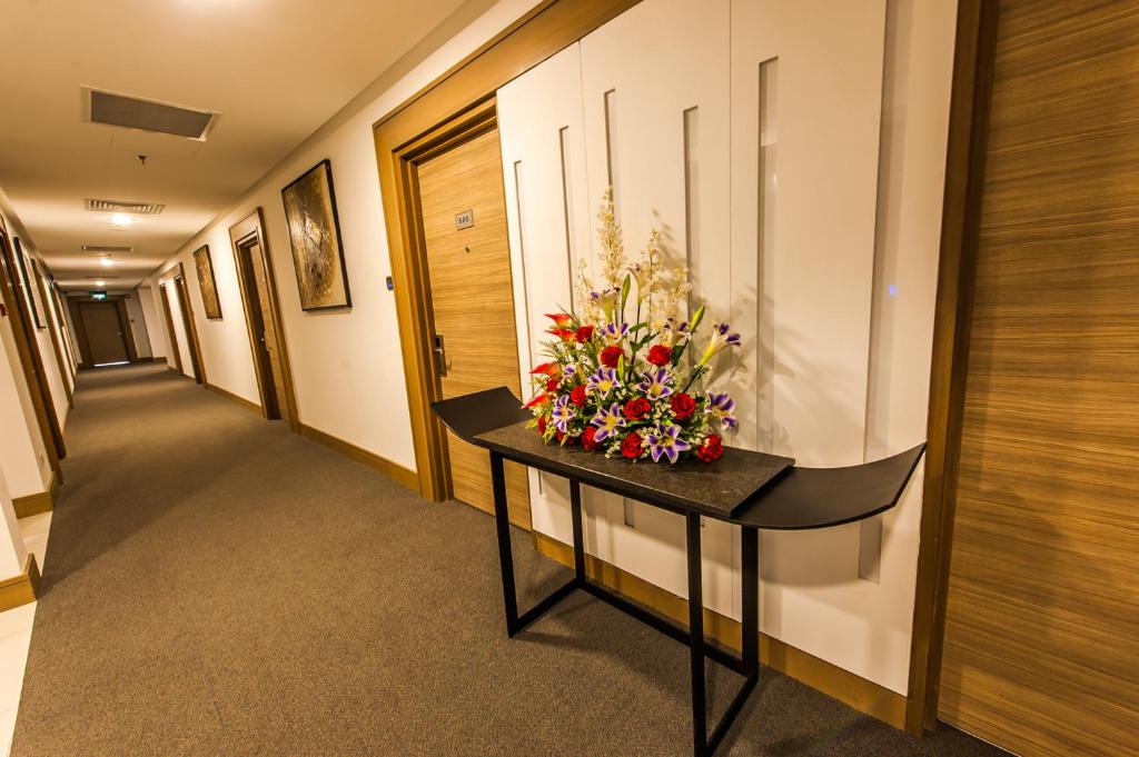 a hallway with a table with a bouquet of flowers on it at Badi'ah Hotel in Bandar Seri Begawan