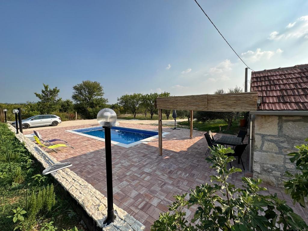 un patio trasero con piscina y una casa en Božini dvori, en Drniš