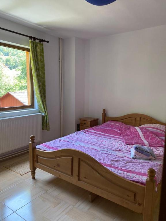 a bedroom with a bed with a purple comforter and a window at Cabana Mario in Albac