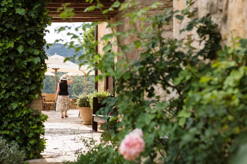 a woman walking down a walkway with an umbrella at La Torre del Visco - Relais & Châteaux in Fuentespalda
